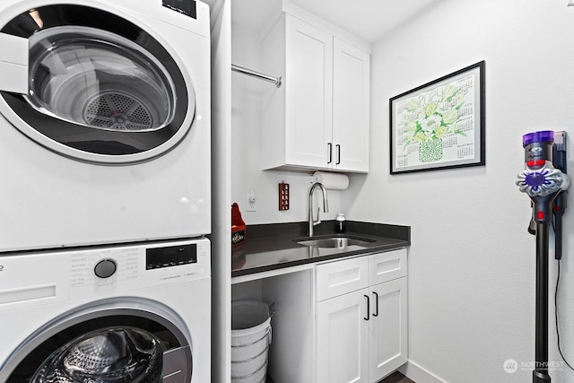 clothes washing area with stacked washer / drying machine, cabinets, and sink