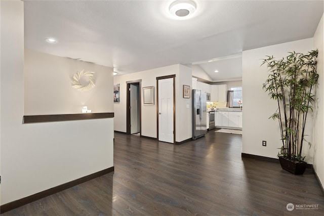 spare room featuring vaulted ceiling and dark wood-type flooring