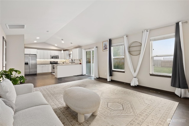 living room featuring sink, dark wood-type flooring, and vaulted ceiling