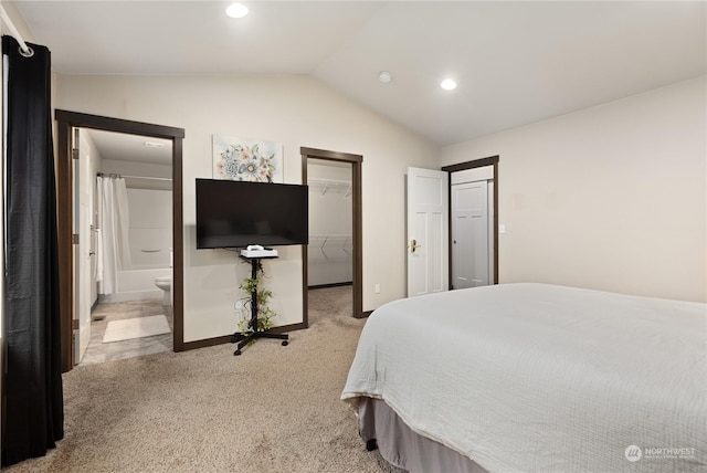 bedroom featuring ensuite bath, a walk in closet, a closet, light colored carpet, and lofted ceiling