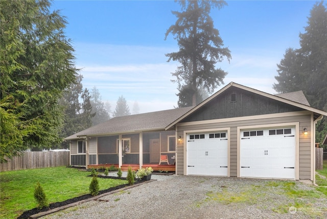 ranch-style house featuring a garage, a sunroom, and a front yard