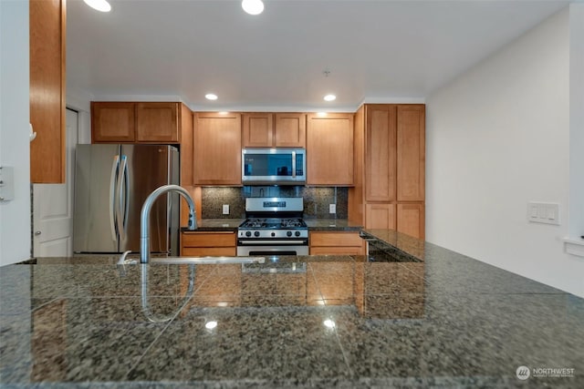 kitchen with tasteful backsplash, sink, dark stone countertops, and stainless steel appliances