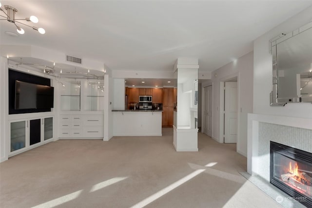 unfurnished living room featuring light carpet, a chandelier, and a fireplace