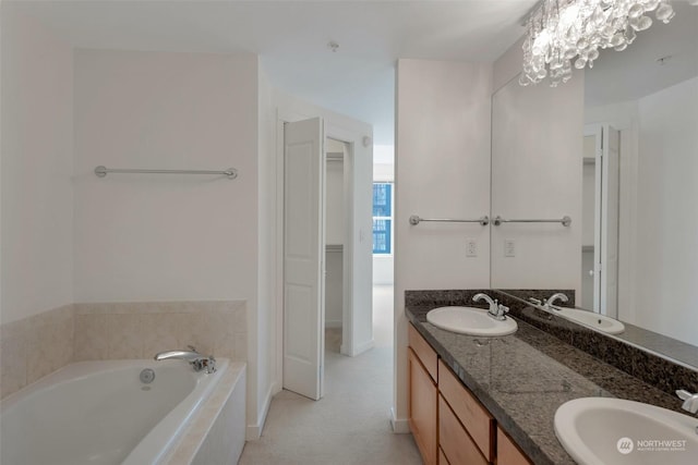 bathroom featuring a relaxing tiled tub, vanity, and an inviting chandelier