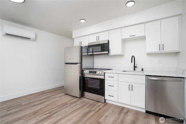kitchen featuring light wood finished floors, a wall mounted air conditioner, appliances with stainless steel finishes, and a sink