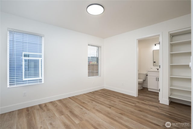 unfurnished bedroom with light wood-type flooring, ensuite bath, and baseboards