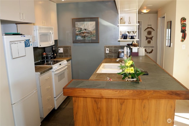 kitchen featuring white appliances, white cabinets, dark tile patterned flooring, decorative backsplash, and sink