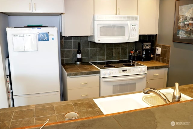 kitchen with white appliances, decorative backsplash, white cabinets, sink, and tile countertops