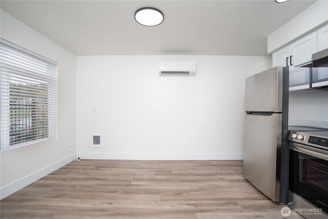 kitchen with visible vents, a wall unit AC, baseboards, appliances with stainless steel finishes, and white cabinetry