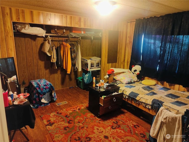 bedroom with hardwood / wood-style flooring and wooden walls