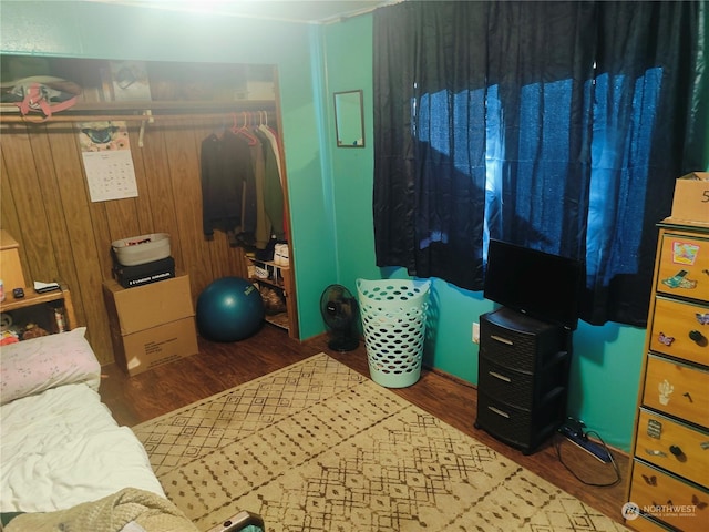 bedroom featuring wooden walls, hardwood / wood-style floors, and a closet