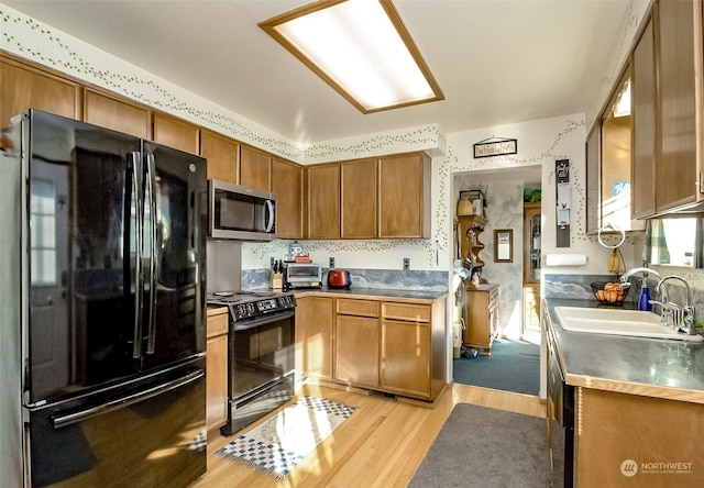 kitchen featuring sink, light hardwood / wood-style flooring, and black appliances