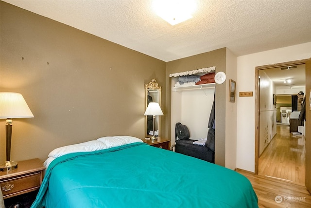 bedroom featuring light hardwood / wood-style flooring, a closet, and a textured ceiling