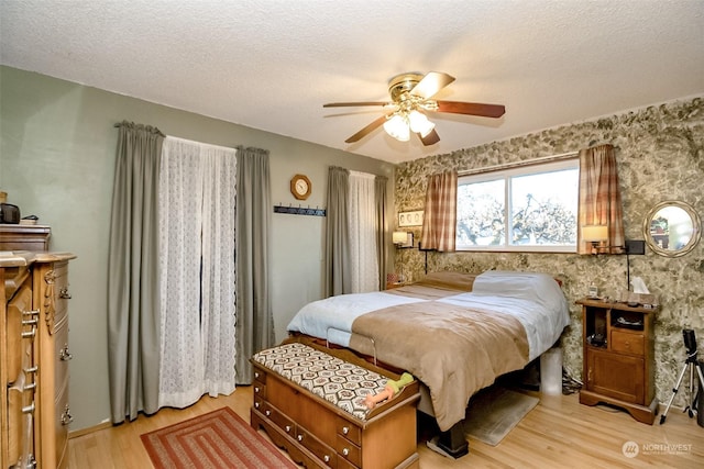 bedroom with a textured ceiling, ceiling fan, and light wood-type flooring