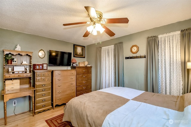 bedroom with light wood-type flooring, a textured ceiling, and ceiling fan