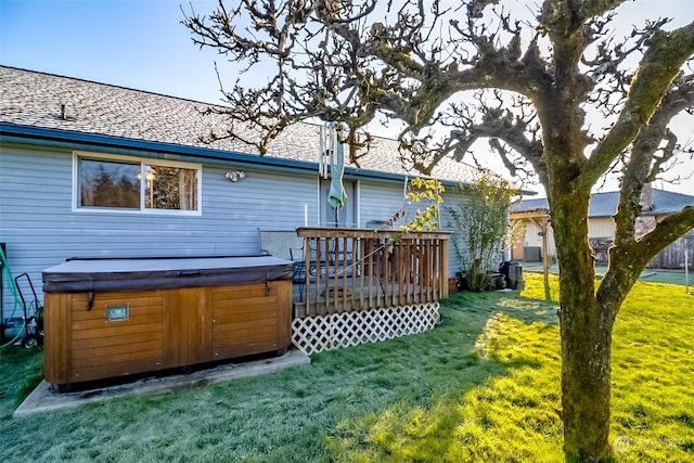 rear view of house with a yard, a hot tub, and a deck