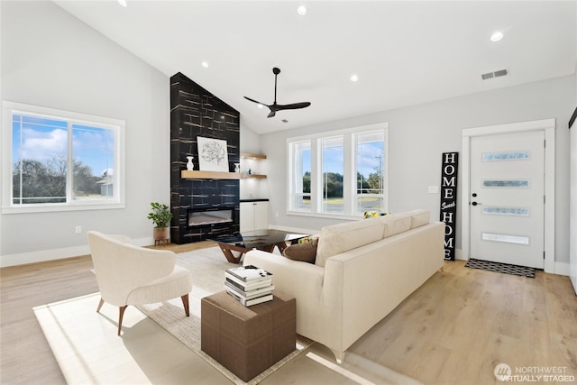 living room with a premium fireplace, recessed lighting, visible vents, and light wood-style floors