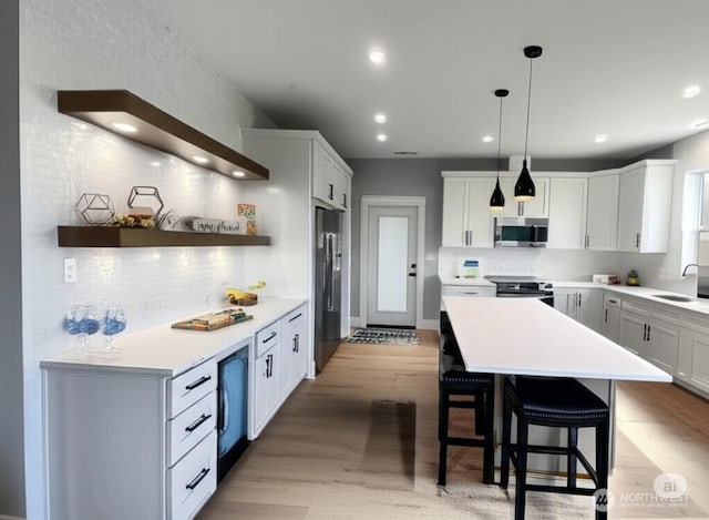 998 Cascade Ave SW, Ocean Shores, WA 98569 - kitchen featuring stainless steel appliances, a sink, light wood-type flooring, backsplash, and a kitchen breakfast bar