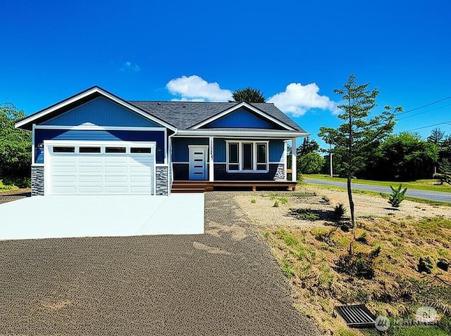 998 Cascade Ave SW, Ocean Shores, WA 98569 - view of front of house featuring driveway, an attached garage, stone siding, and a porch