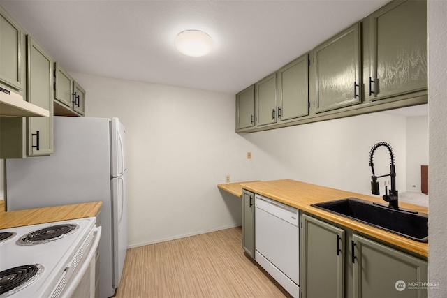 kitchen with sink, white appliances, light hardwood / wood-style floors, and green cabinets