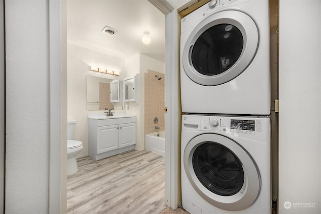 laundry room with stacked washer and dryer and light wood-type flooring