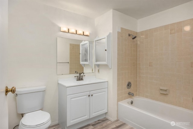 full bathroom featuring vanity, hardwood / wood-style floors, tiled shower / bath combo, and toilet