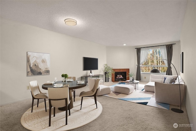 living room with a tiled fireplace, carpet floors, and a textured ceiling