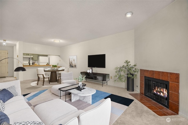 carpeted living room featuring a tiled fireplace and a textured ceiling