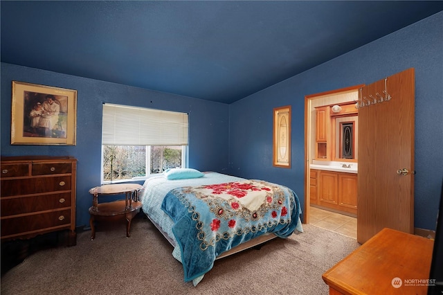 bedroom with vaulted ceiling, sink, light colored carpet, and ensuite bathroom