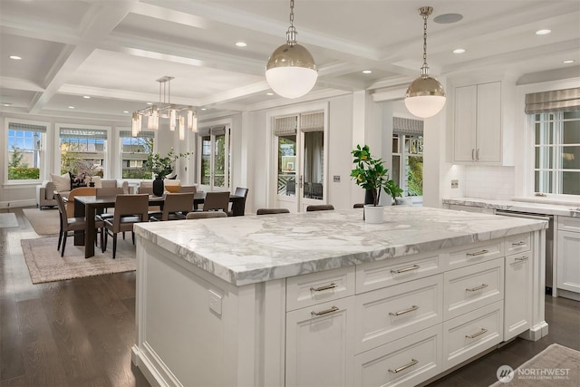 kitchen with dark wood-type flooring, coffered ceiling, white cabinets, and a center island