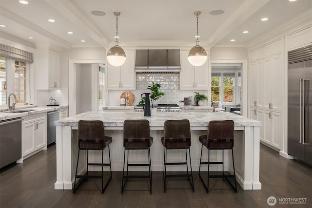 kitchen featuring stainless steel appliances, white cabinetry, a sink, and wall chimney exhaust hood