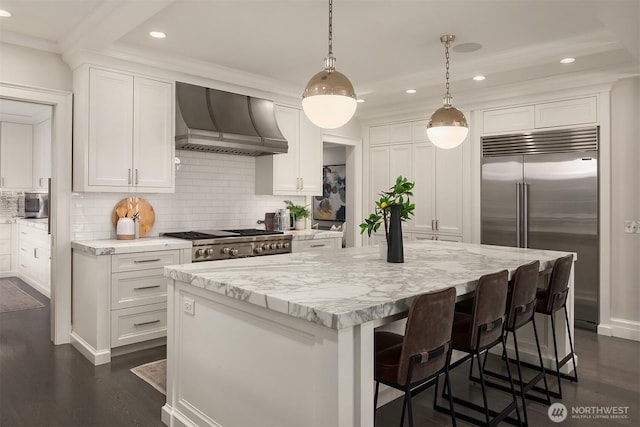 kitchen featuring wall chimney exhaust hood, backsplash, white cabinetry, and stainless steel built in fridge