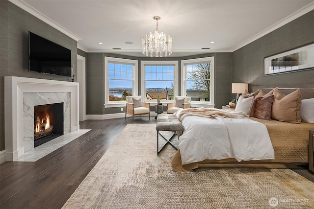 bedroom featuring baseboards, a fireplace, wood finished floors, and crown molding