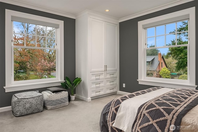 bedroom with baseboards, crown molding, and light colored carpet