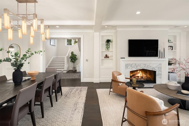 living room featuring built in shelves, recessed lighting, dark wood-style flooring, a fireplace, and stairs