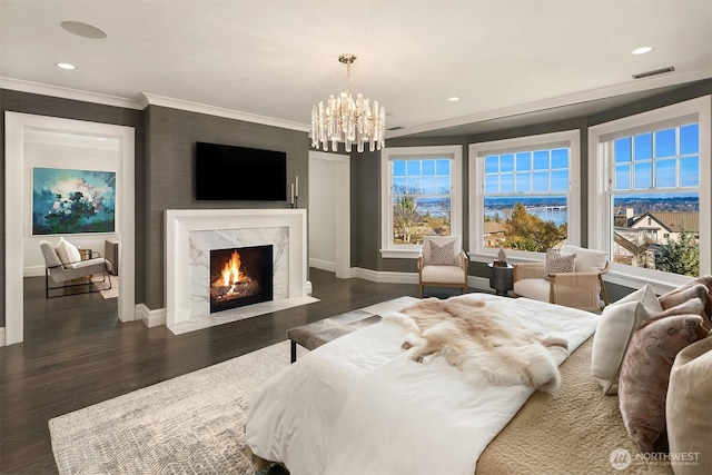 bedroom featuring a premium fireplace, visible vents, a chandelier, and wood finished floors