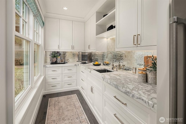 kitchen featuring a wealth of natural light, stainless steel fridge, a sink, and open shelves