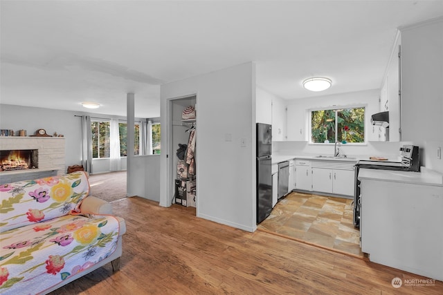 kitchen with a wealth of natural light, appliances with stainless steel finishes, white cabinetry, and sink