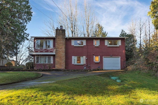 rear view of house with a garage, a lawn, and a balcony