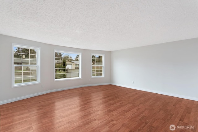 spare room featuring a textured ceiling, baseboards, and wood finished floors