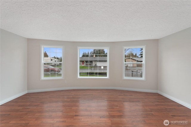 unfurnished room featuring wood finished floors, baseboards, and a textured ceiling