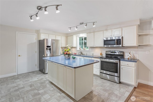 kitchen with open shelves, stainless steel appliances, white cabinets, dark countertops, and a center island