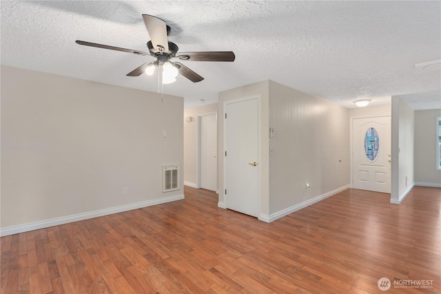 spare room featuring visible vents, baseboards, wood finished floors, and a ceiling fan