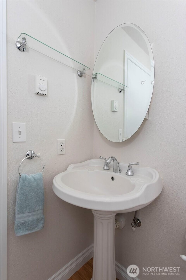 bathroom with a sink, baseboards, and wood finished floors