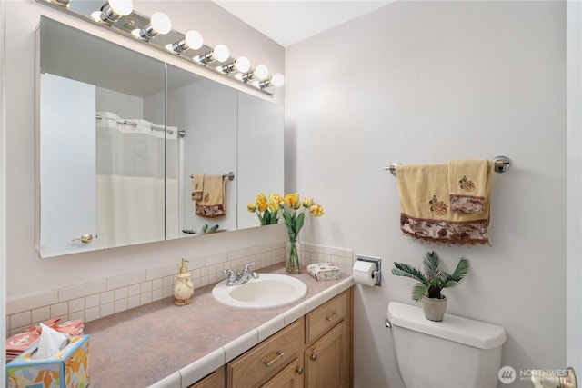 bathroom featuring toilet, vanity, and a shower with curtain