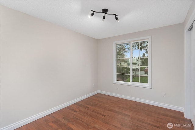 empty room featuring baseboards, a textured ceiling, and wood finished floors