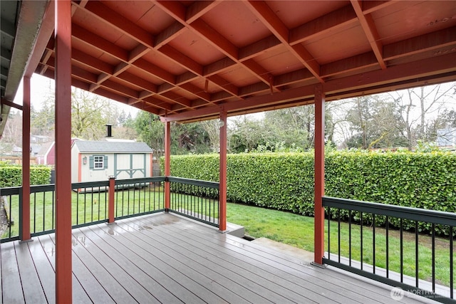 wooden deck featuring a shed, a lawn, and an outdoor structure