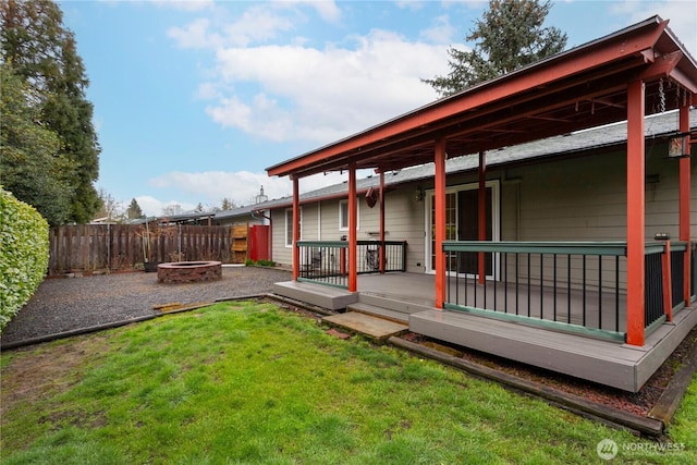 view of yard featuring a deck, fence, and an outdoor fire pit