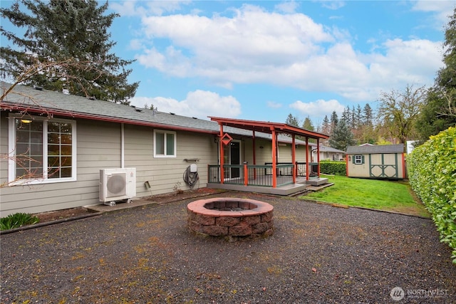 back of house featuring an outbuilding, a wooden deck, an outdoor fire pit, a storage unit, and ac unit