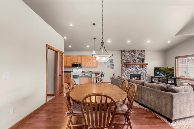 dining room with dark hardwood / wood-style flooring and a stone fireplace